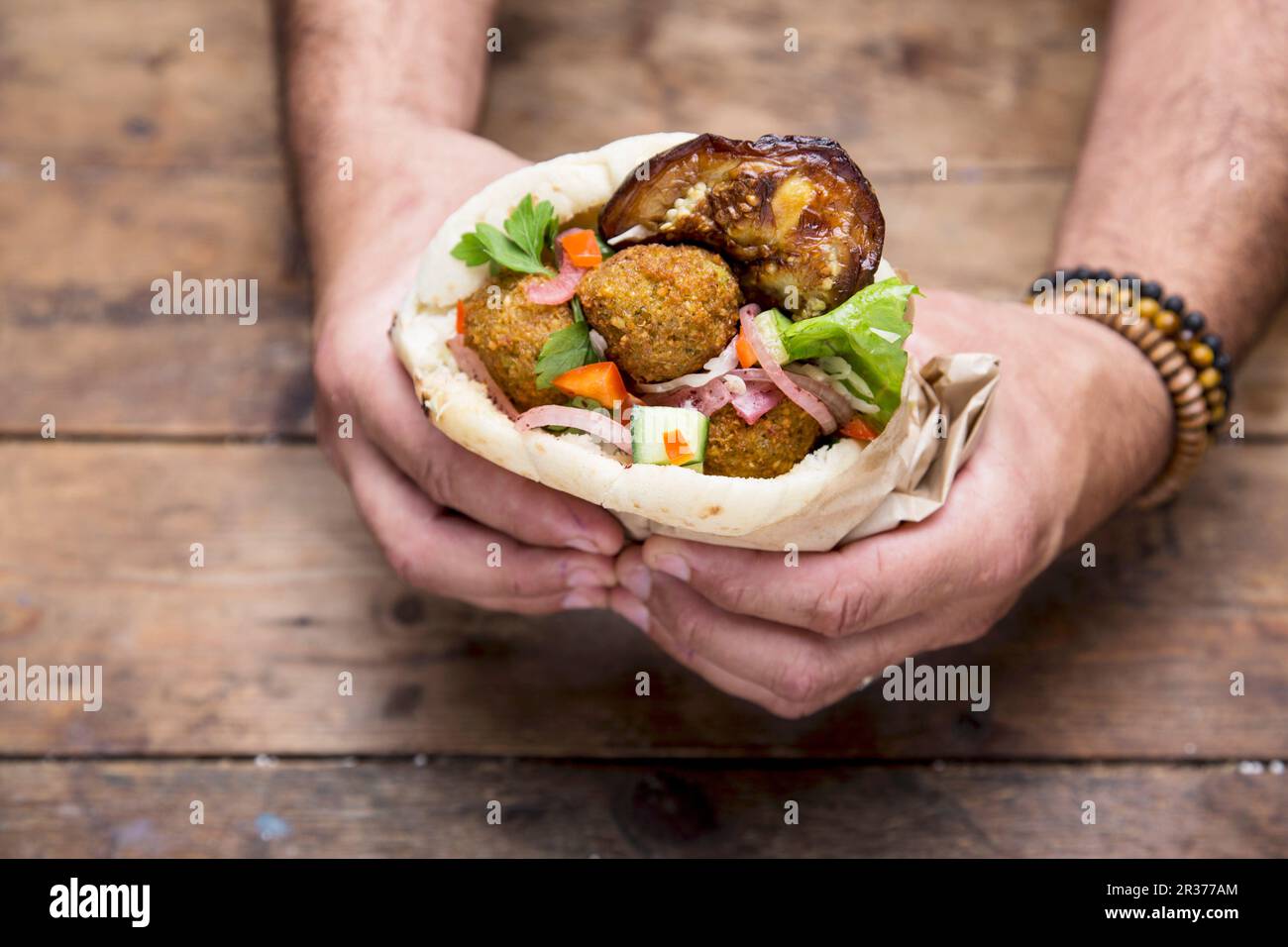 Hands holding a pita bread with falafel Stock Photo