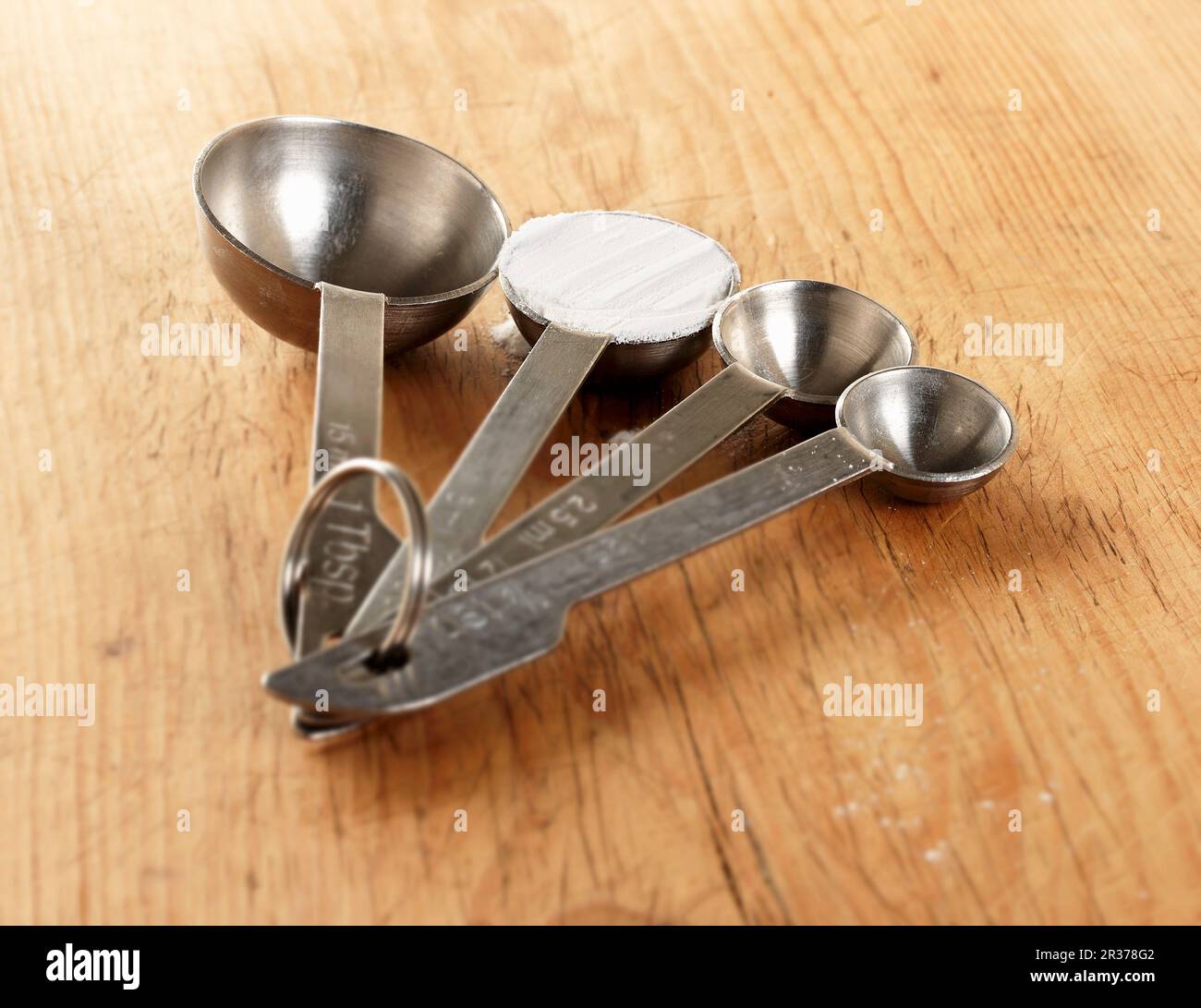 https://c8.alamy.com/comp/2R378G2/four-measuring-spoons-one-showing-a-level-teaspoon-of-baking-powder-shot-on-a-wooden-surface-2R378G2.jpg
