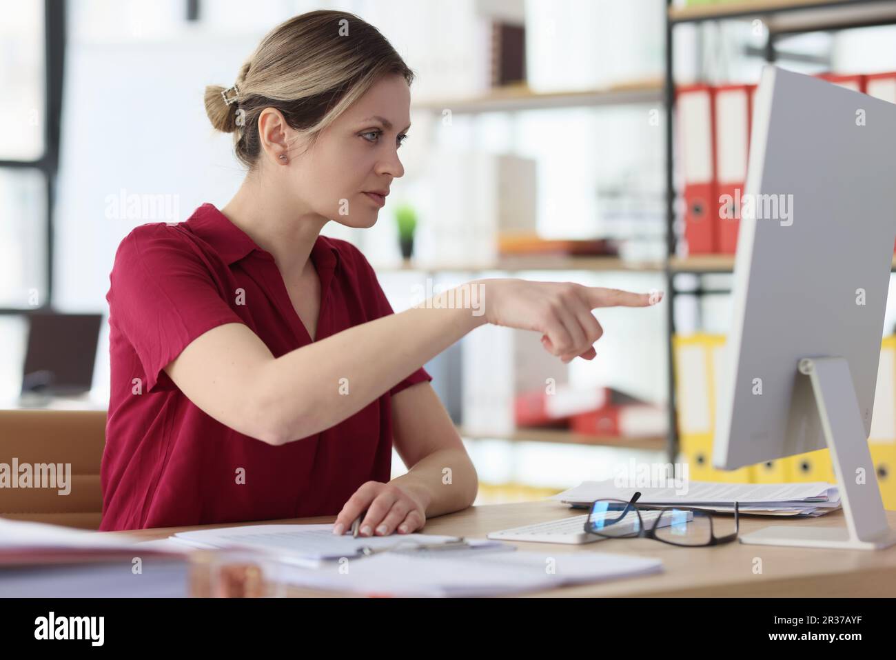 Serious female points finger to computer monitor on error Stock Photo ...