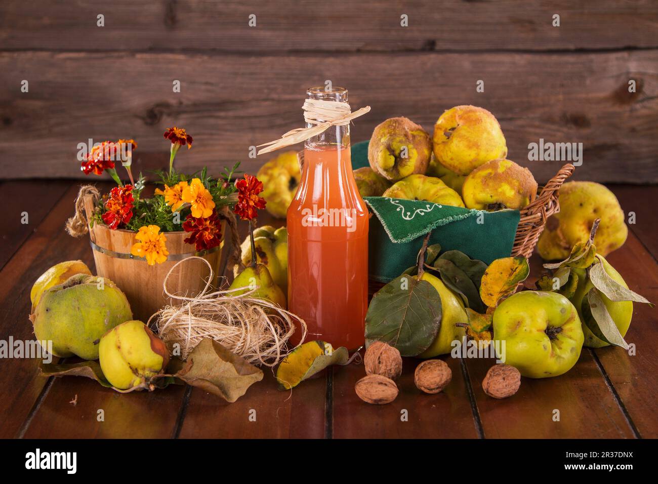 Still life with quinces, quince juice, walnuts and flowers Stock Photo