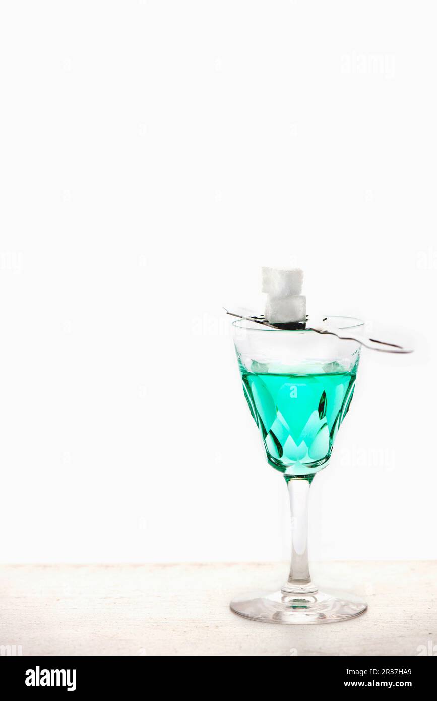 Absinthe with an absinthe spoon and sugar cubes in a crystal glass