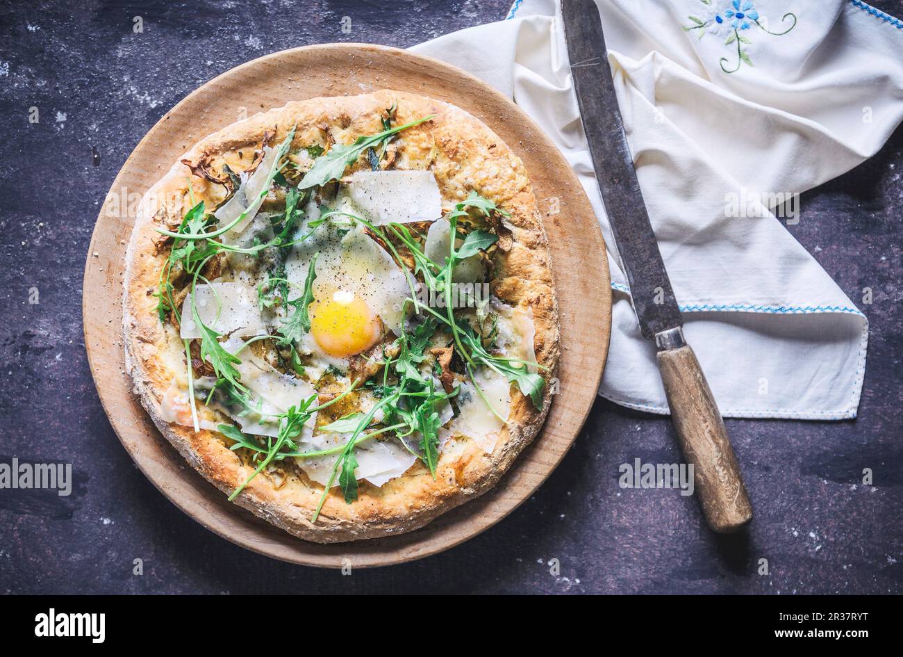 A pizza with rocket, fried egg and parmesan (seen from above) Stock Photo