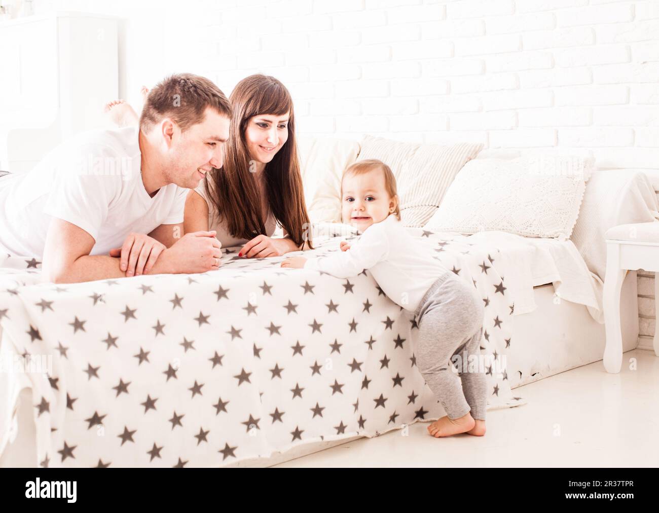 Parents teach the child to climb on the bed Stock Photo Alamy