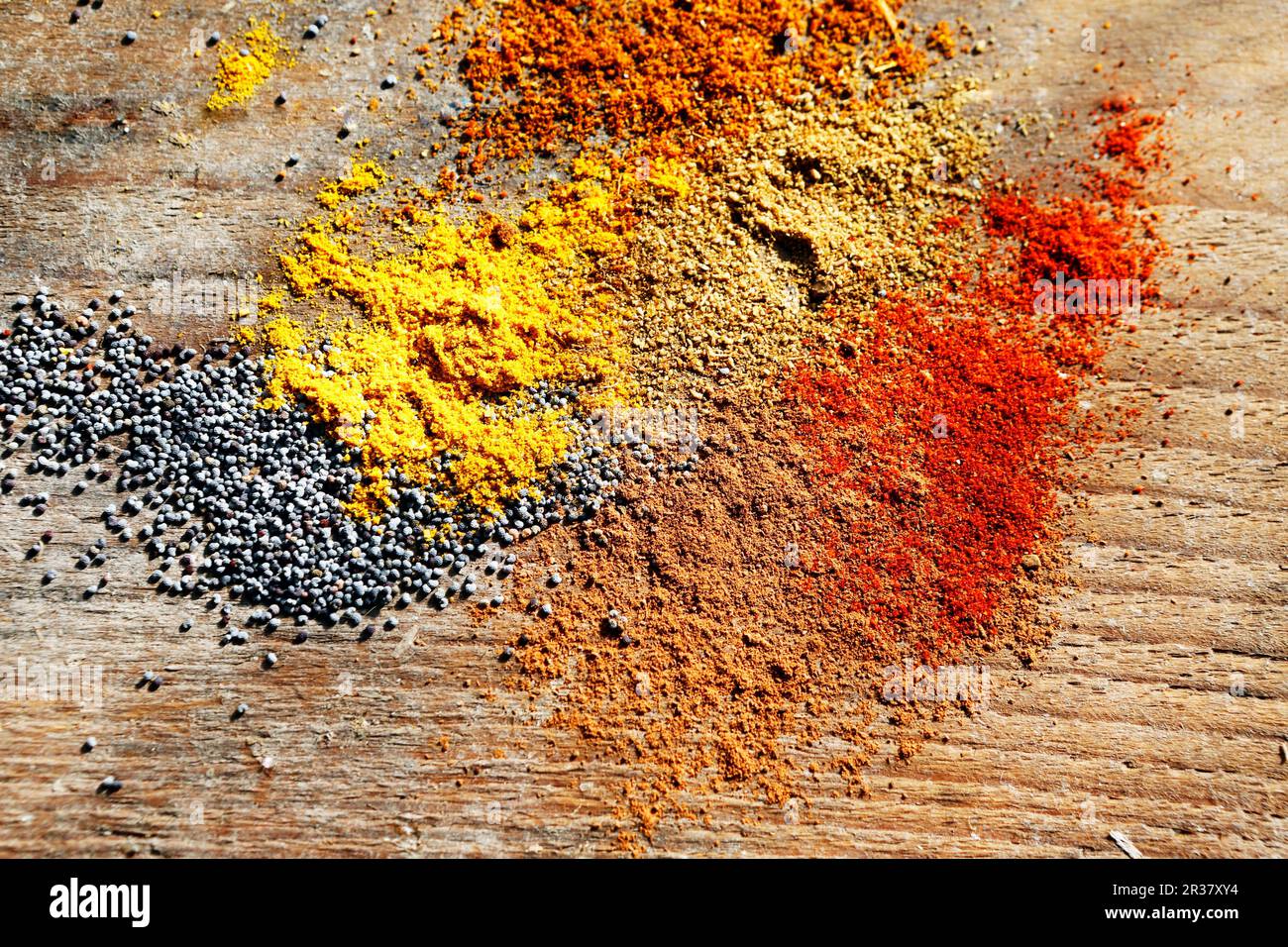 Various spices and poppyseeds on a wooden surface Stock Photo