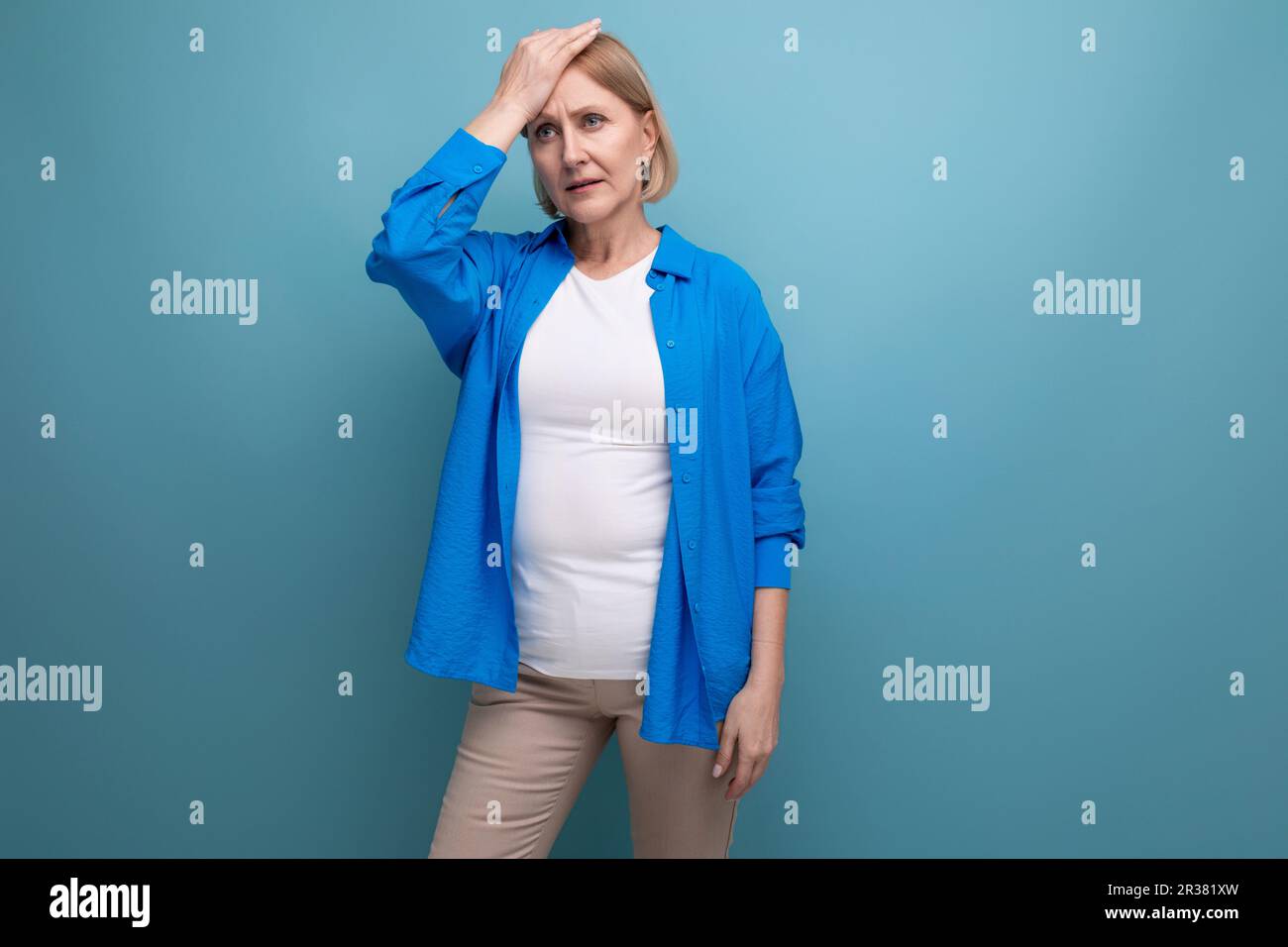 smart mature woman thinking brilliant idea on blue background with copyspace Stock Photo