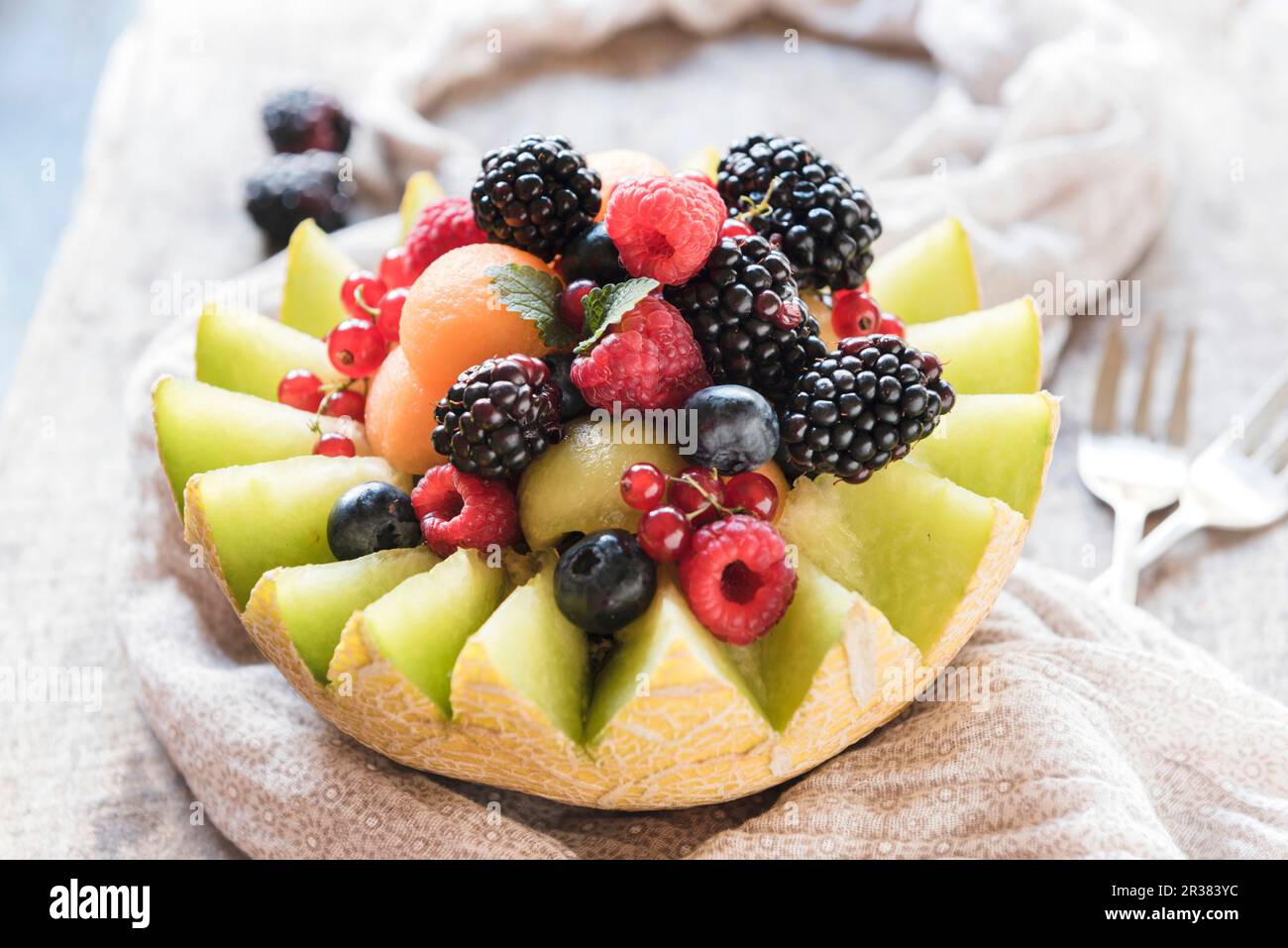 A halved melon filled with melon balls and fresh berries Stock Photo