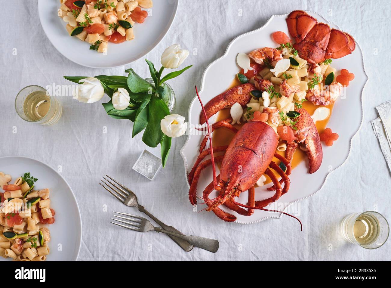 Lobster with rigatoni on a table decorated with a vase of tulips (seen from above) Stock Photo