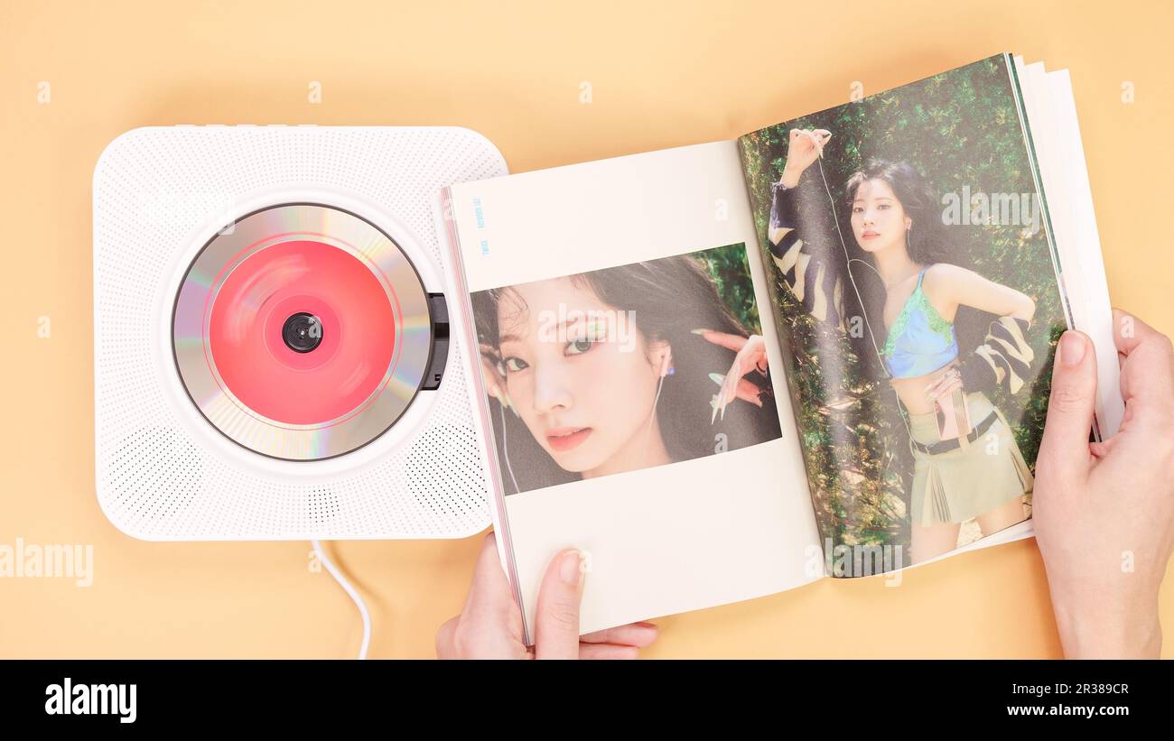 Hands holding Twice Between 1 and 2 mini Album photobook on yellow. Music CD player. South Korean girl group Twice. Space for text. Gatineau, QC Canad Stock Photo