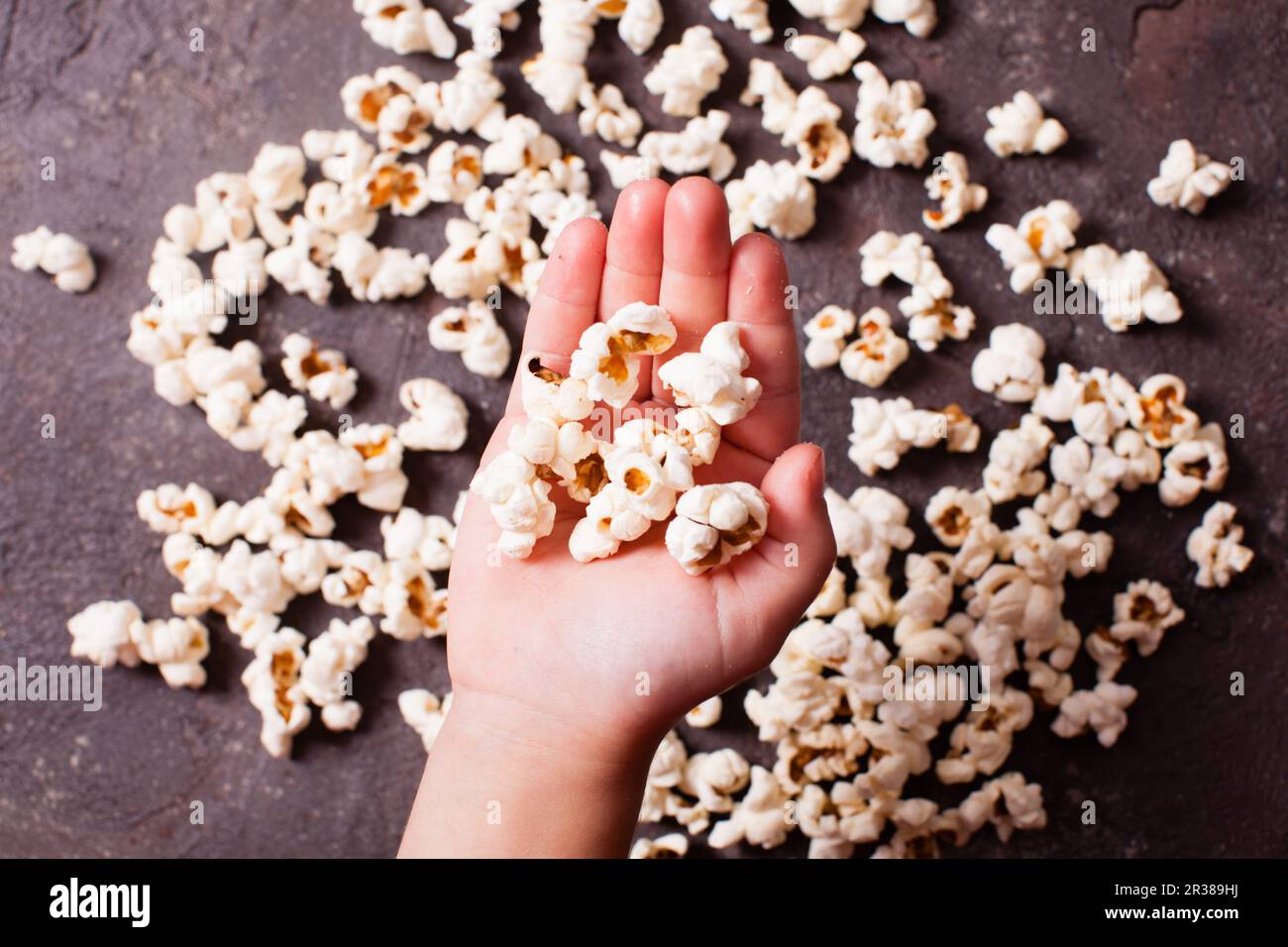 Children's hand holds popcorn Stock Photo