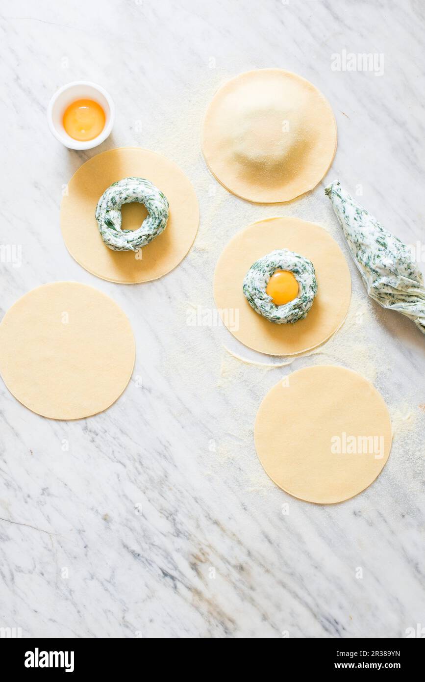 Making of breakfast spinach and ricotta ravioli with egg yolk, using