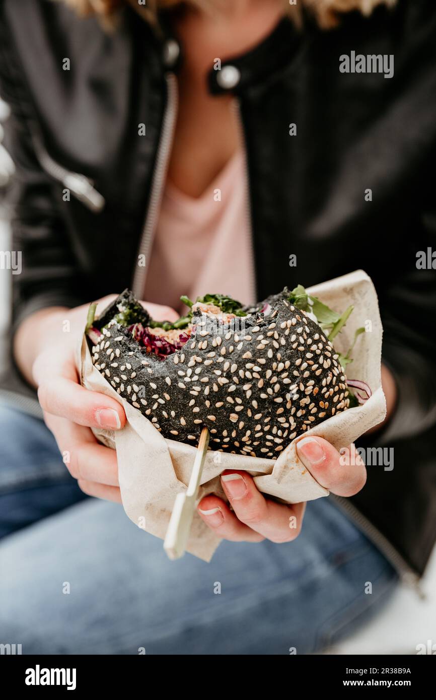 Close up of woman hands holding delicious organic salmon vegetarian burger on open air beer an burger urban street food festival in Ljubljana, Slovenia Stock Photo