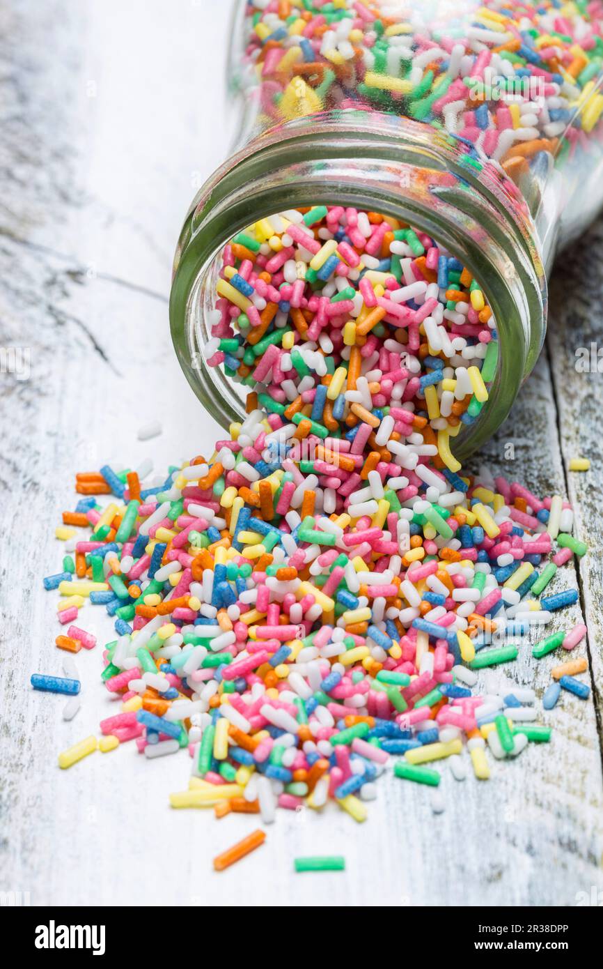 Colourful sprinkles spilling out of a jar Stock Photo