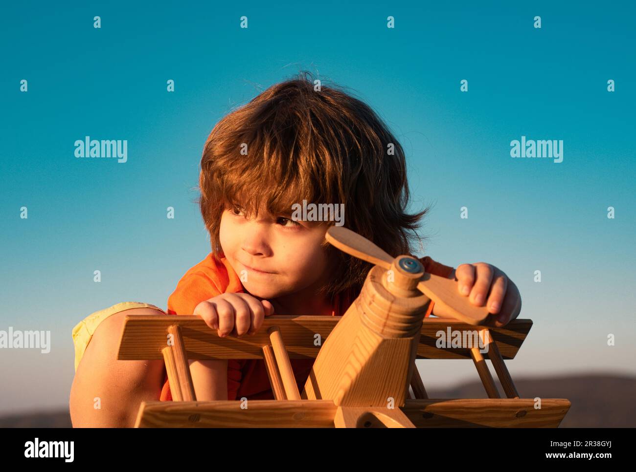 Child boy playing with wooden toy airplane, dream of a pilot