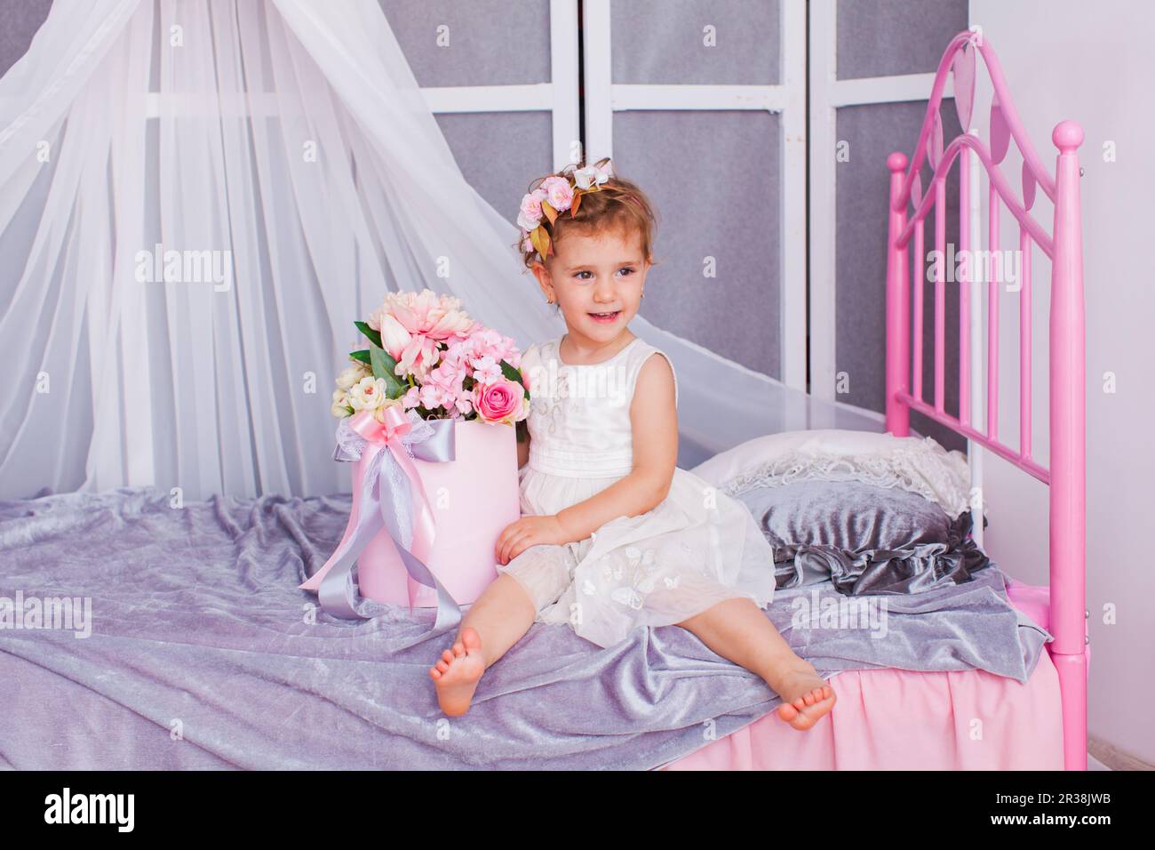 Baby girl sitting on her bed wearing headband Stock Photo Alamy