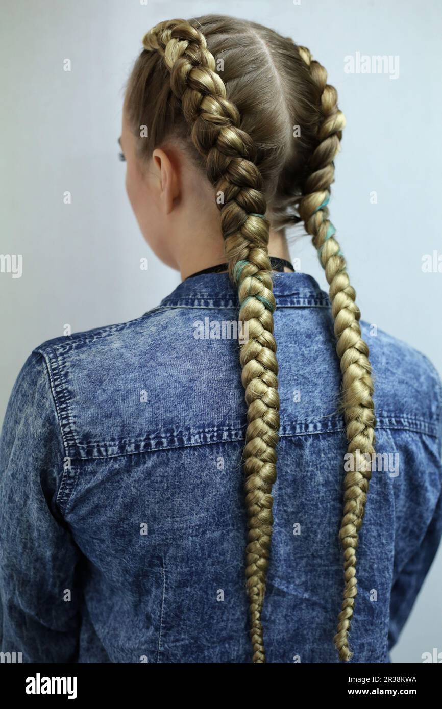 Two thick braids with a kanekalon on light hair, a youth hairsty Stock Photo