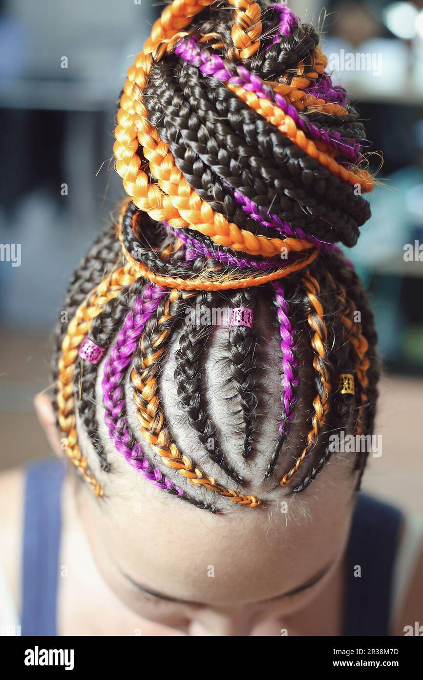 Pigtails orange and brown with artificial hair braided and collected in a high tail, close-up hairstyles on the head of a girl Stock Photo