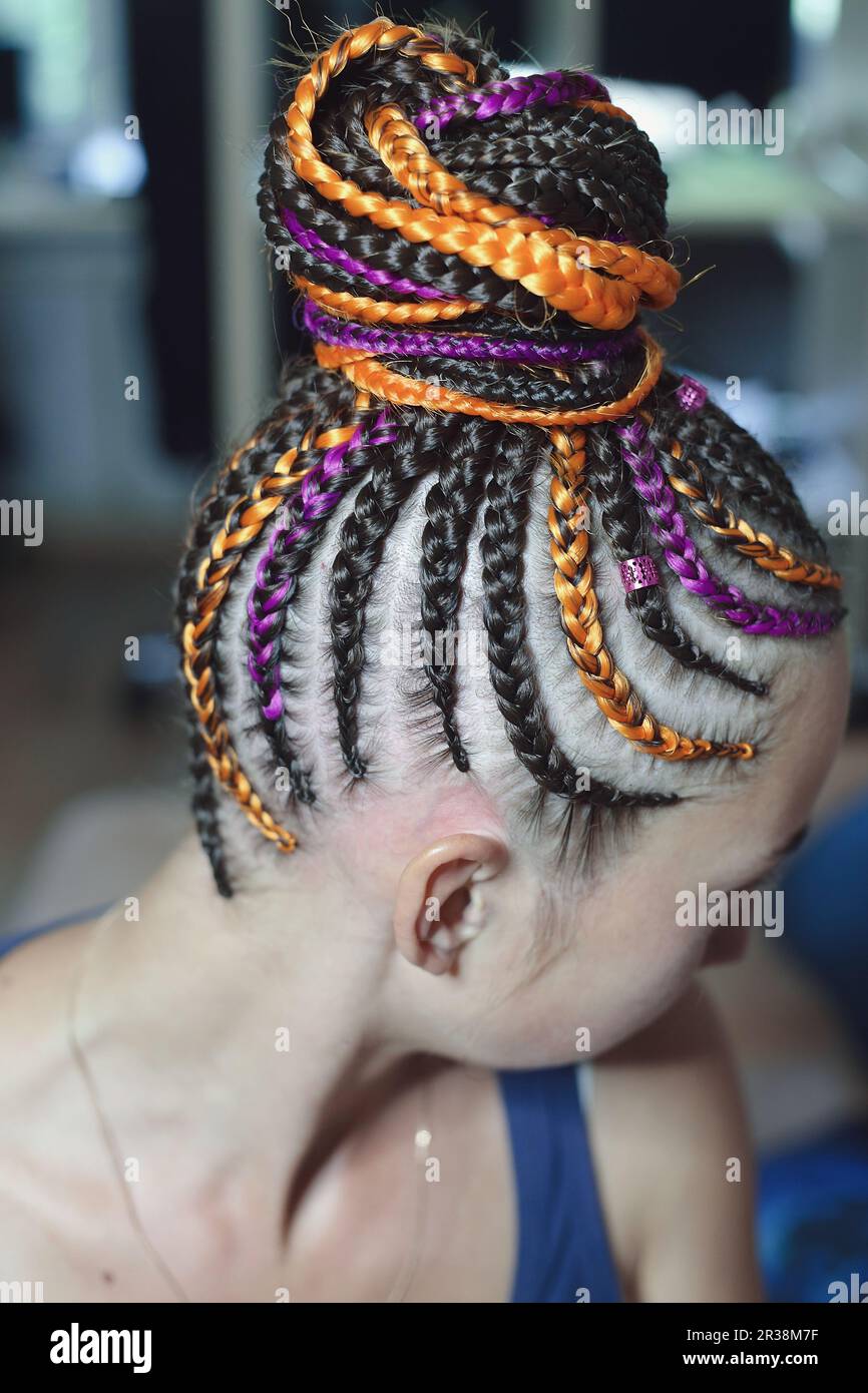 Pigtails orange and brown with artificial hair braided and collected in a high tail, close-up hairstyles on the head of a girl Stock Photo