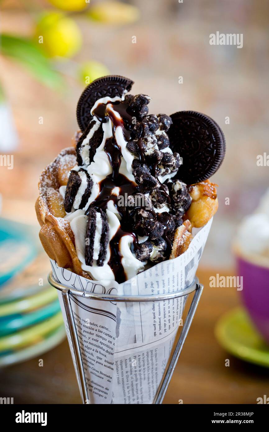 A bubble waffle with frozen yoghurt, Oreo cookies, Oreo popcorn and chocolate sauce Stock Photo