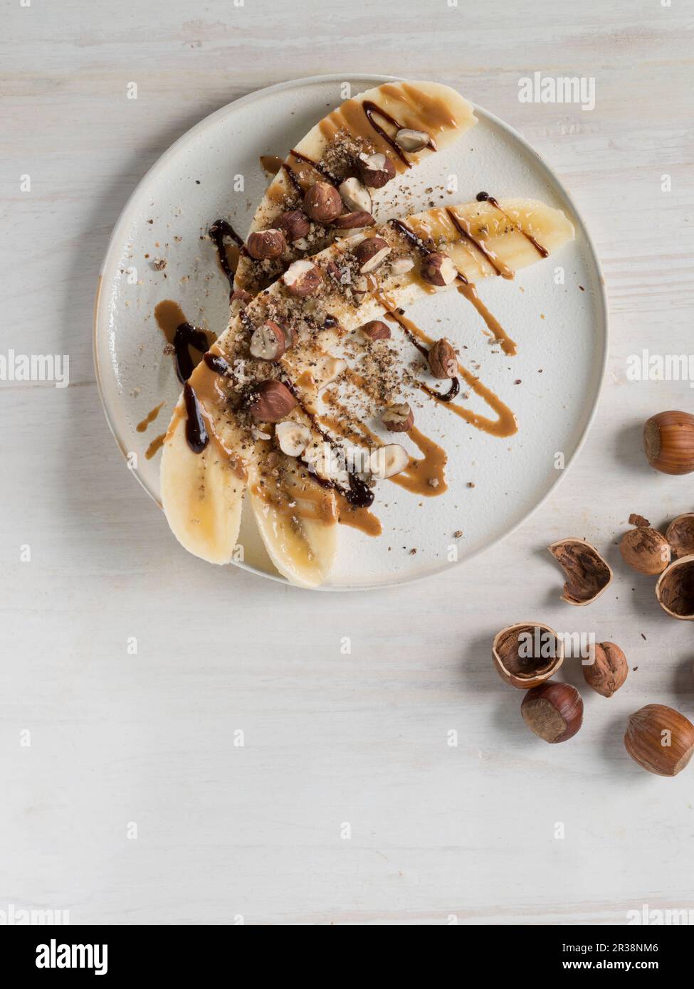 Halved bananas with hazelnuts, hazelnut butter and chocolate sauce
