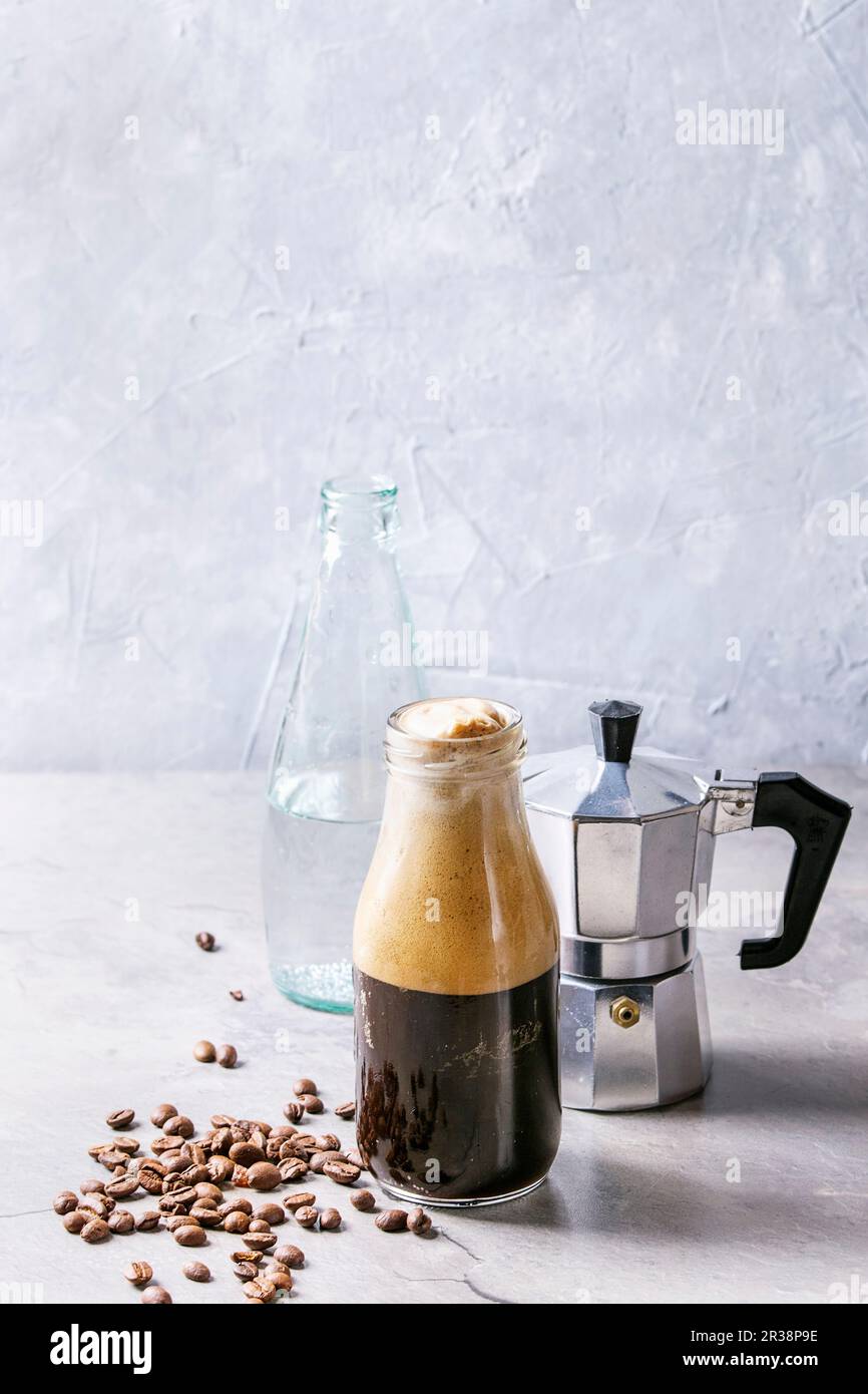 Bottle of fizzy iced Coffee espresso with bottle of sparkling water, coffee maker and roasted
