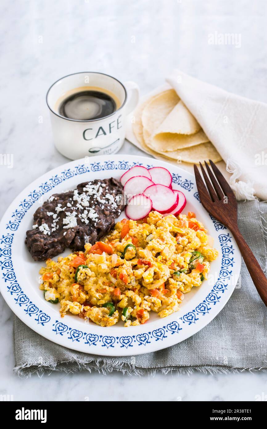 Huevos a la mexicana - Mexican scrambled eggs with tomatoes, onions and green chilli peppers served with fried beans, tortillas and coffee (tipical me Stock Photo