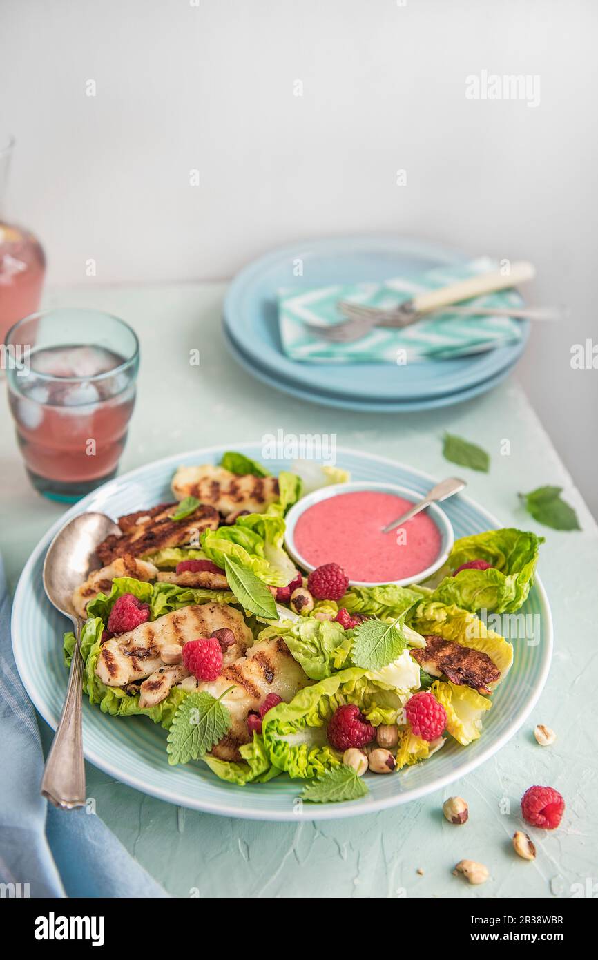 Grilled hallumi salad with little gem lettuce, raspberry dressing, fresh raspberries, hazelnuts and verbena mint Stock Photo