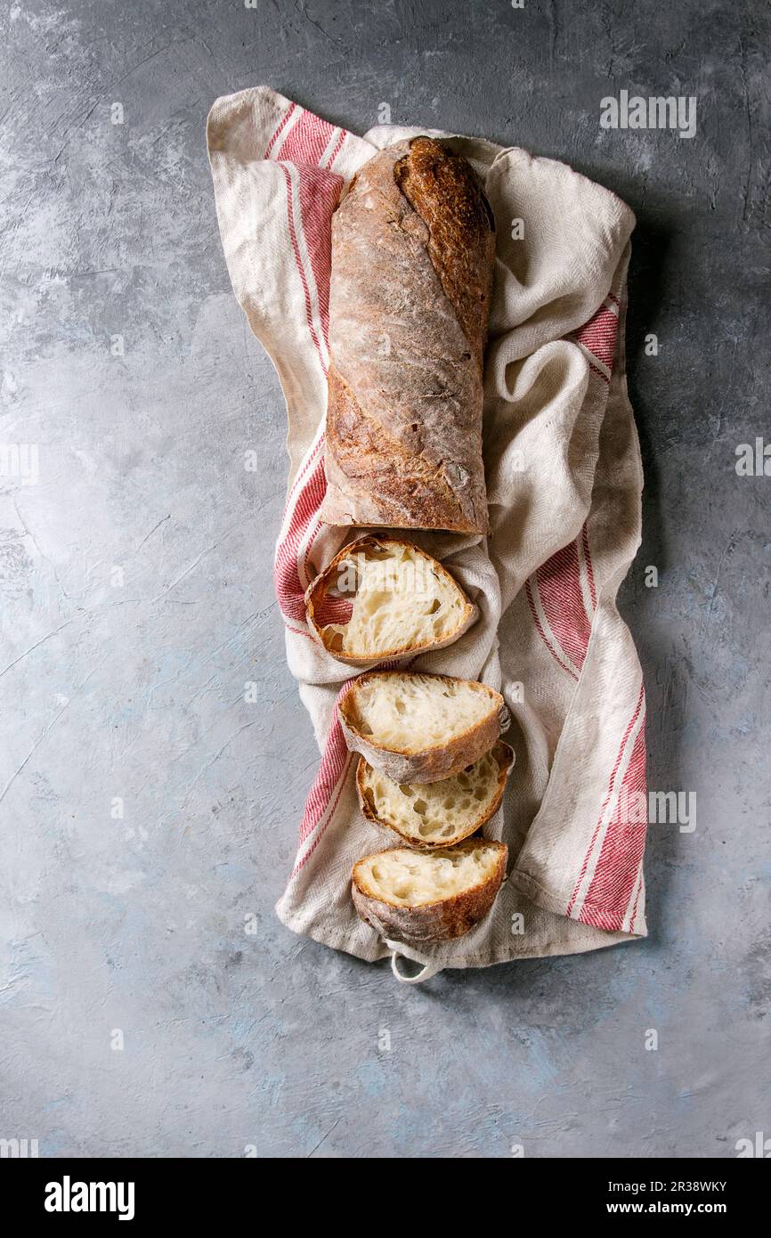 Sliced fresh baked artisan whole grain ciabatta bread on kitchen towel ...