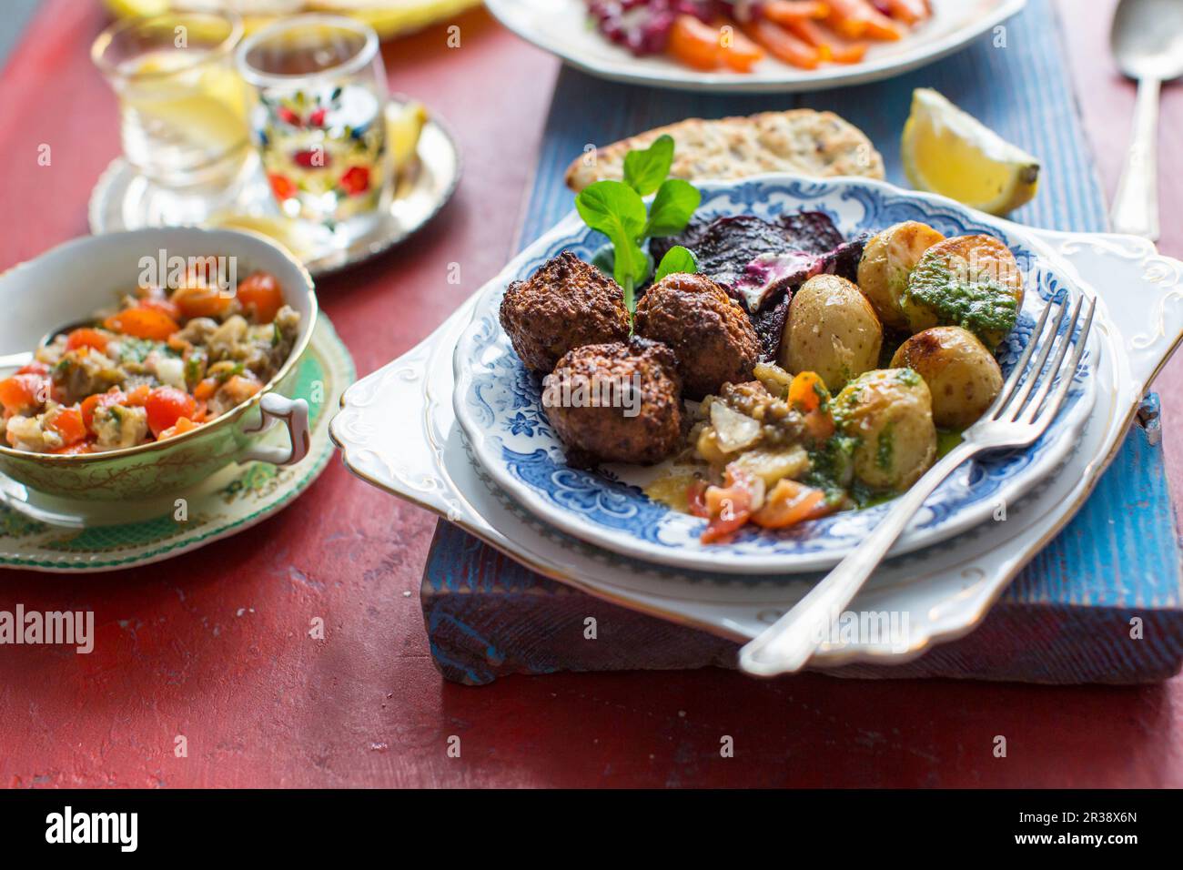 Middle easterrn supper with chickpea falafel, mutabal dip, roast potatoes and beetroot crips Stock Photo
