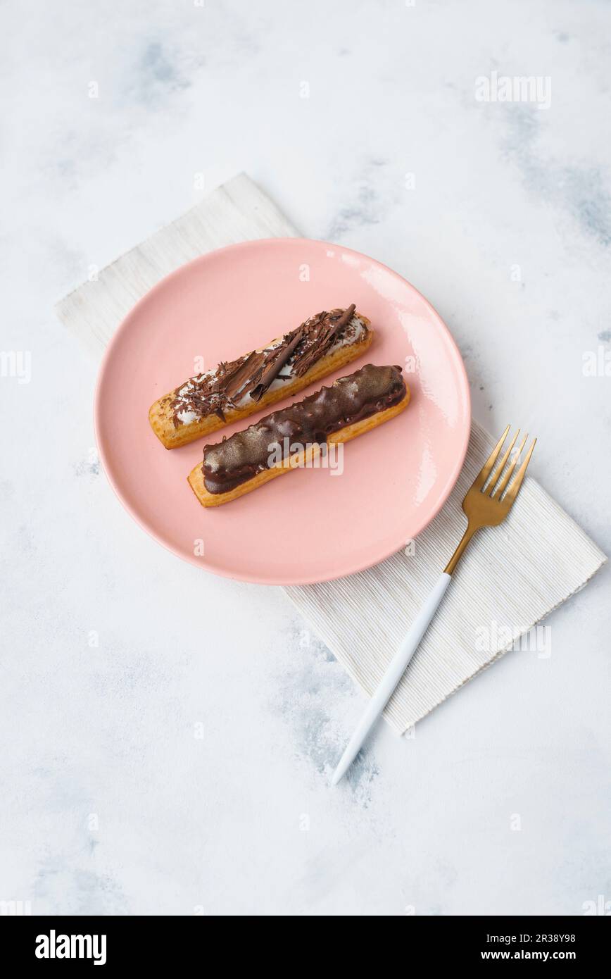 Two eclairs on a pink plate Stock Photo