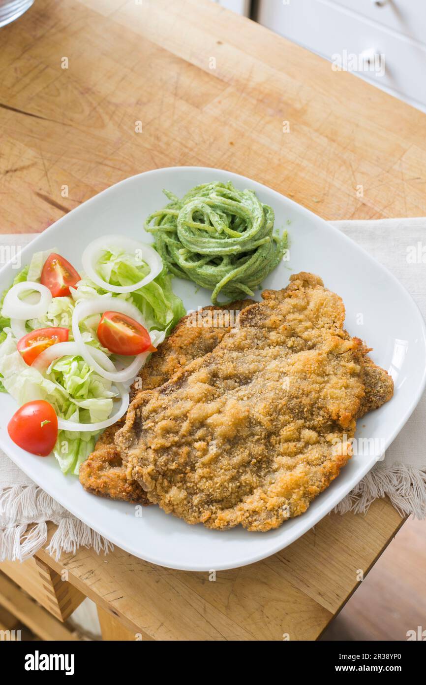 Breaded schnitzel with salad and herb spaghetti Stock Photo
