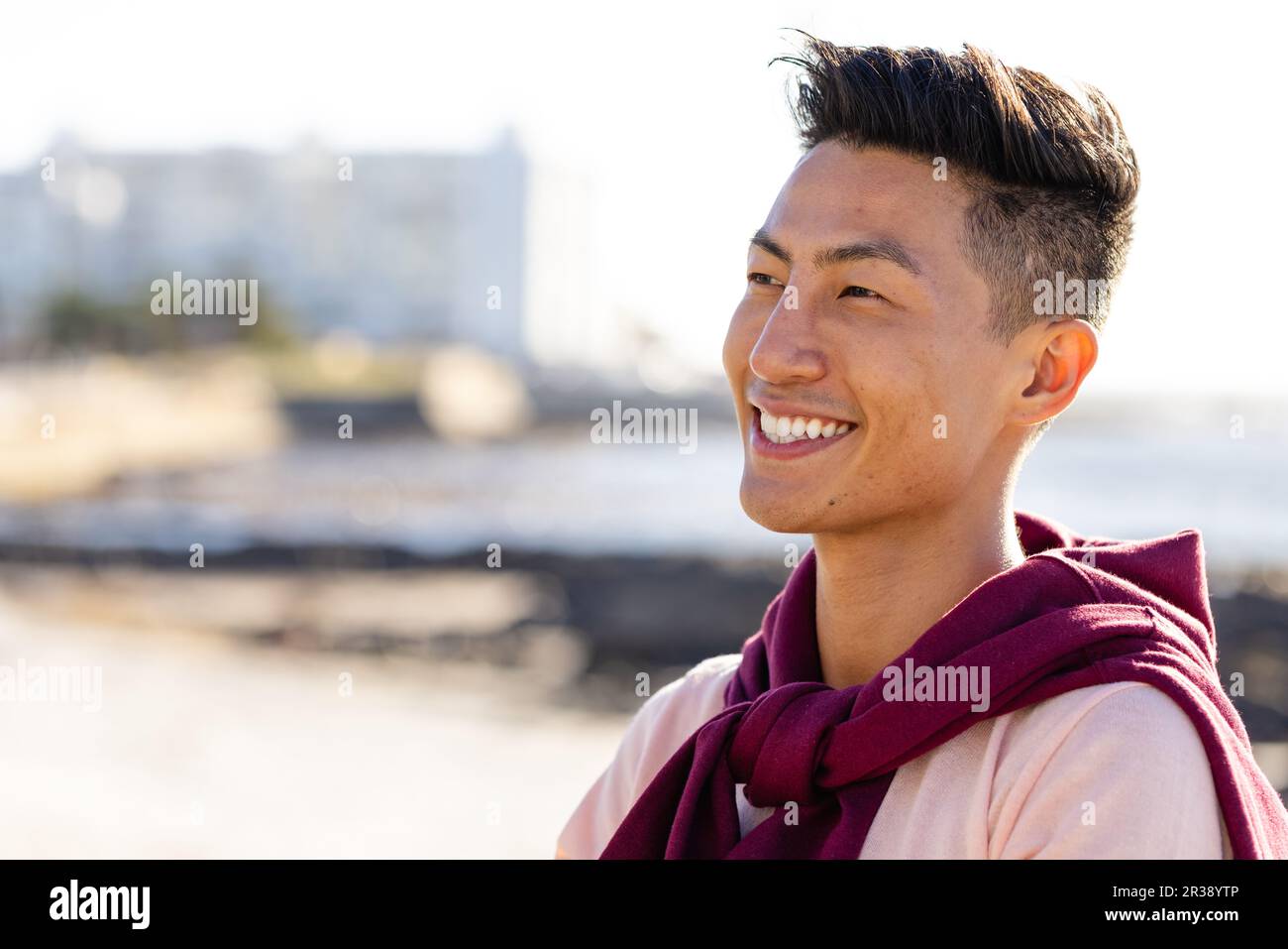 Happy biracial man looking away and smiling on beach, with copy space Stock Photo