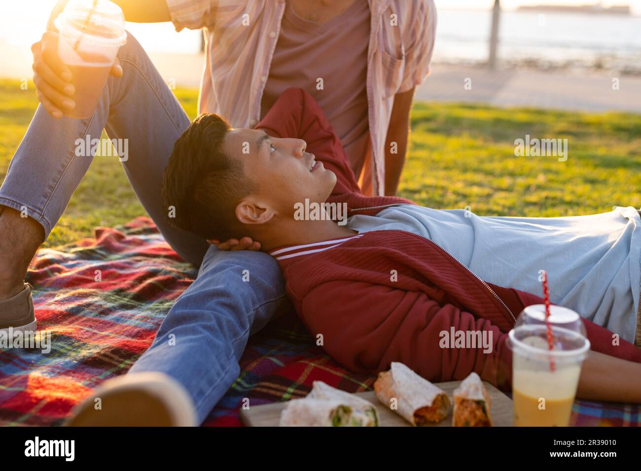 Happy biracial gay male couple having picnic on promenade by the sea at sundown Stock Photo Alamy