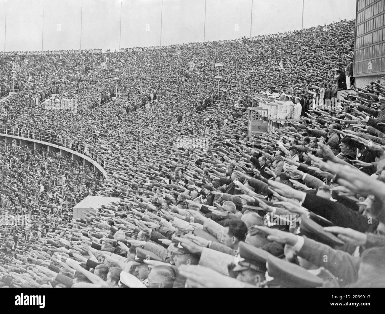 Berlin Olympics 1936. The 1936 Summer Olympics (German: Olympische Sommerspiele 1936), officially known as the Games of the XI Olympiad (German: Spiele der XI. Olympiade) and commonly known as Berlin 1936, were an international multi-sport event held from 1 to 16 August 1936 in Berlin, Germany.  Pictured Olympiastadion in Berlin a stadium built for the 1936 summer olympics with room for 100 000 people and the grand opening of the olympic games 1 august 1936. People are seen doing the Nazi salut, also known as the Hitler salut, a gesture that was at the time used as a greeting in Nazi Germany. Stock Photo