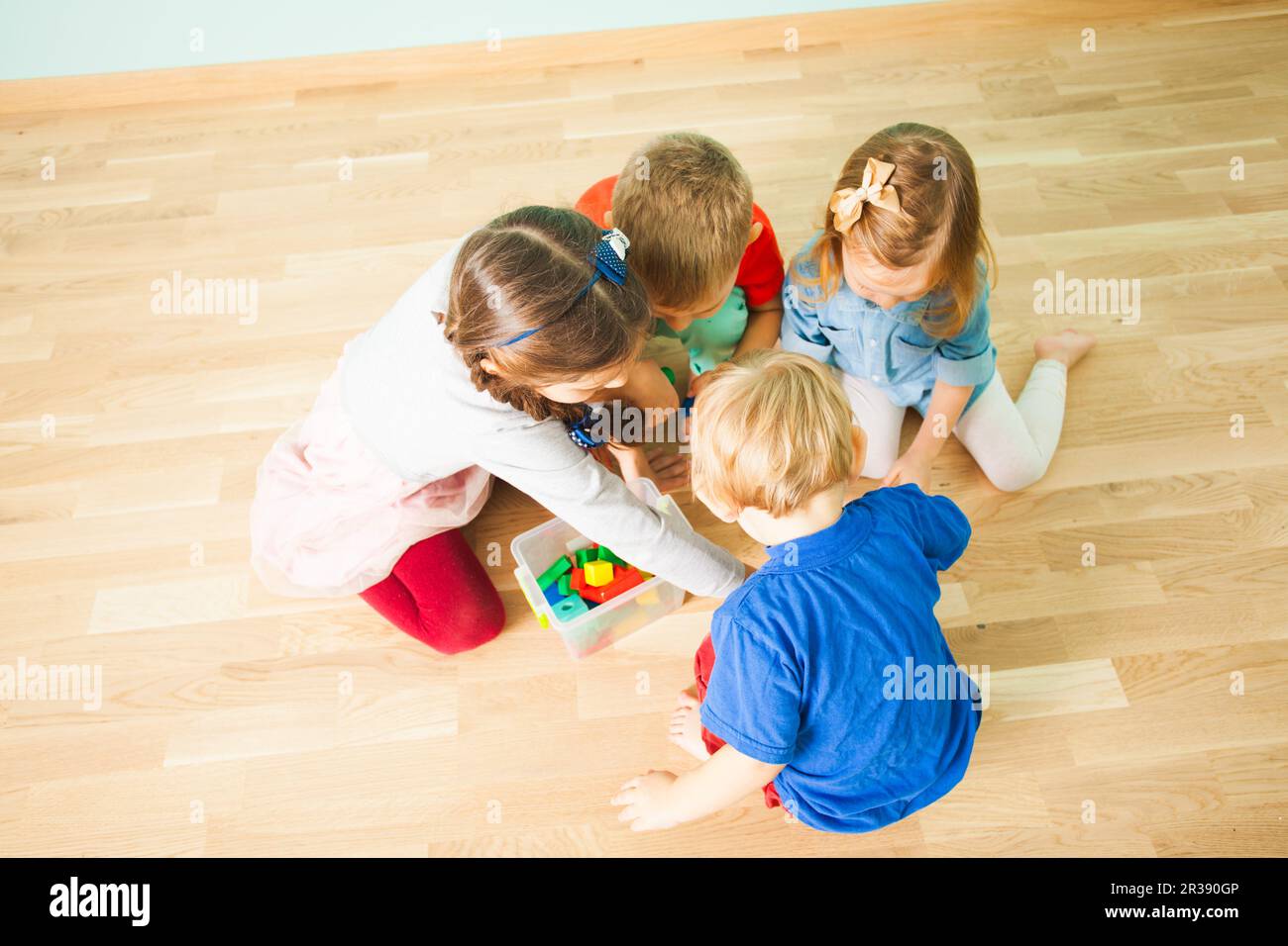 Four little siblings collecting toys in plastic box Stock Photo
