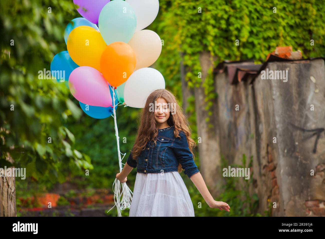Girl is running with colorful balloons outdoors Stock Photo