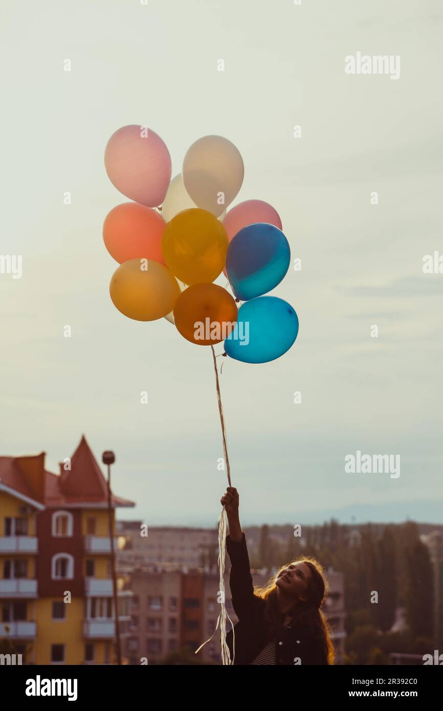Girl with colorful balloons walking on the sunset Stock Photo - Alamy