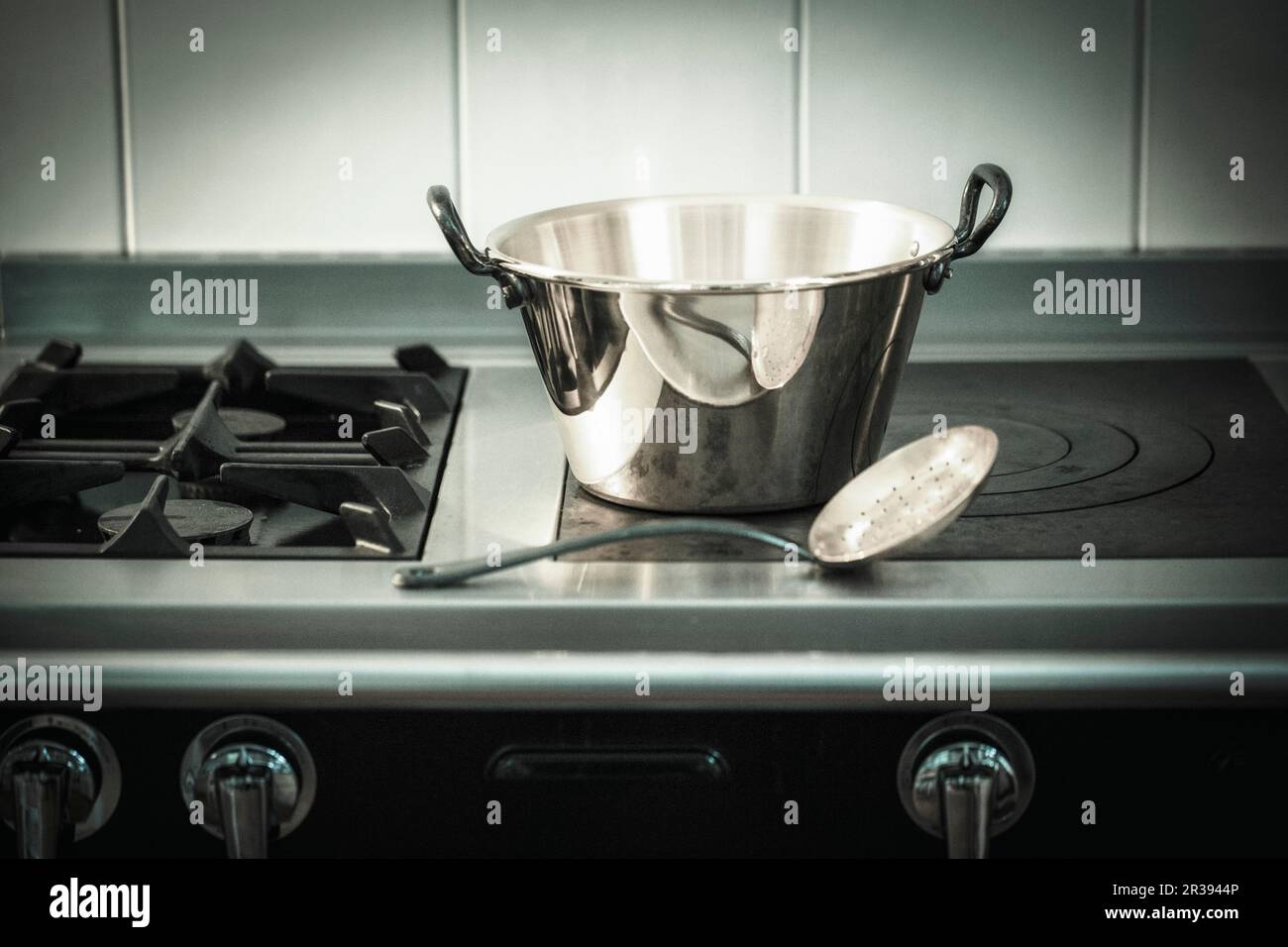 https://c8.alamy.com/comp/2R3944P/an-aluminium-pot-and-a-draining-spoon-on-a-hob-2R3944P.jpg