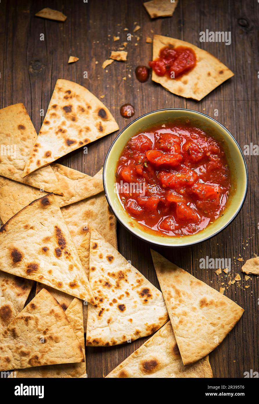Small bowl and tomato salsa served with handmade tortilla chips on a rustic wooden board Stock Photo