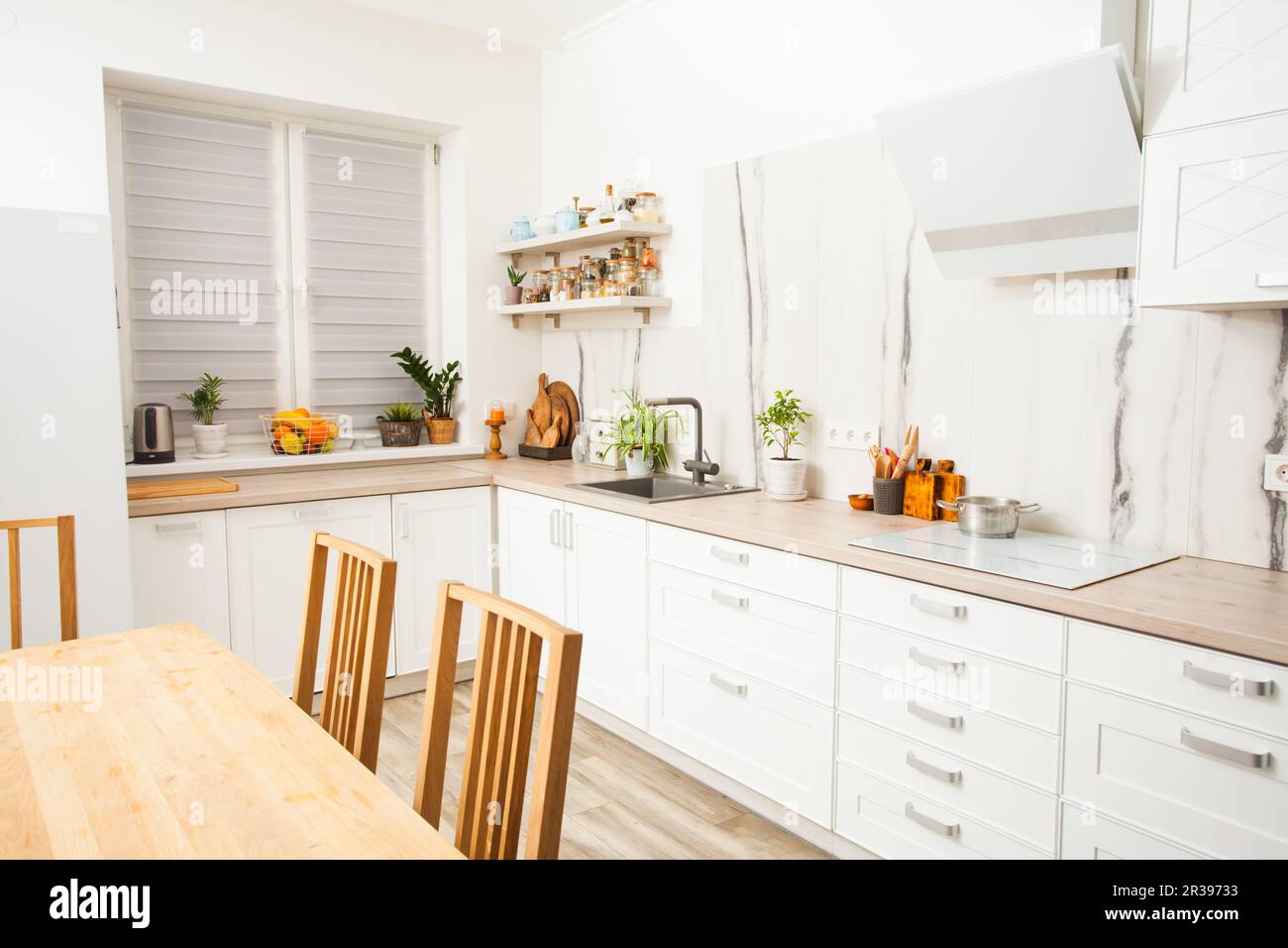 Sunny and bright kitchen with white marble wall. Stock Photo