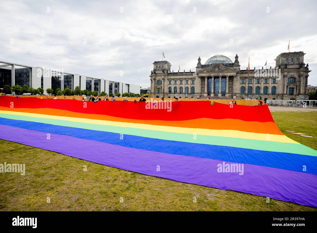 Berlin, Germany. 23rd May, 2023. Participants of an action of the initiative 'Basic Law for All' for the rights and constitutional protection of the rights of queer people hold a huge rainbow flag in front of the Reichstag building. According to the initiative, it is the largest rainbow flag in Germany in terms of area. Credit: Christoph Soeder/dpa/Alamy Live News Stock Photo