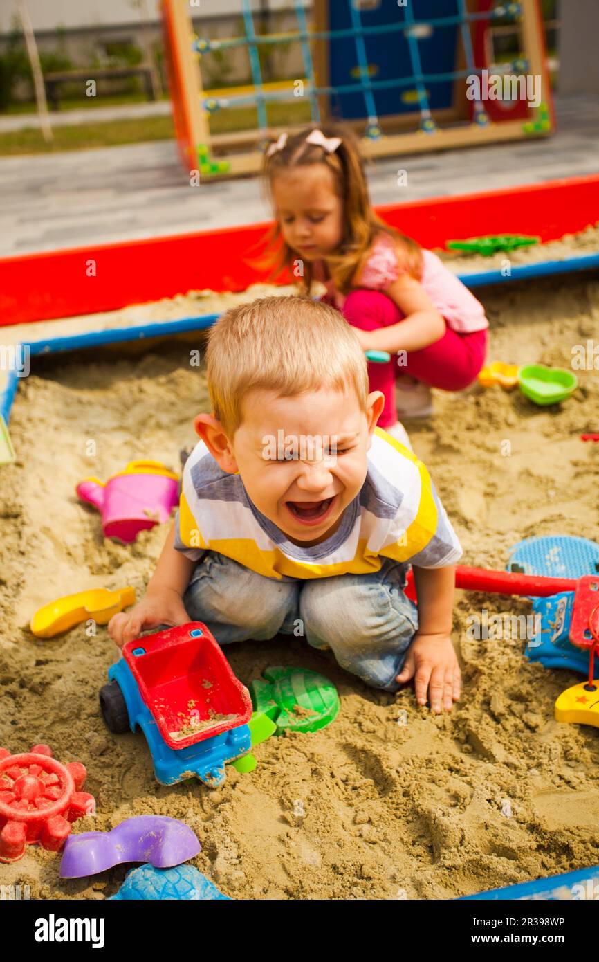 Crying unhappy boy play with car in sandbox Stock Photo