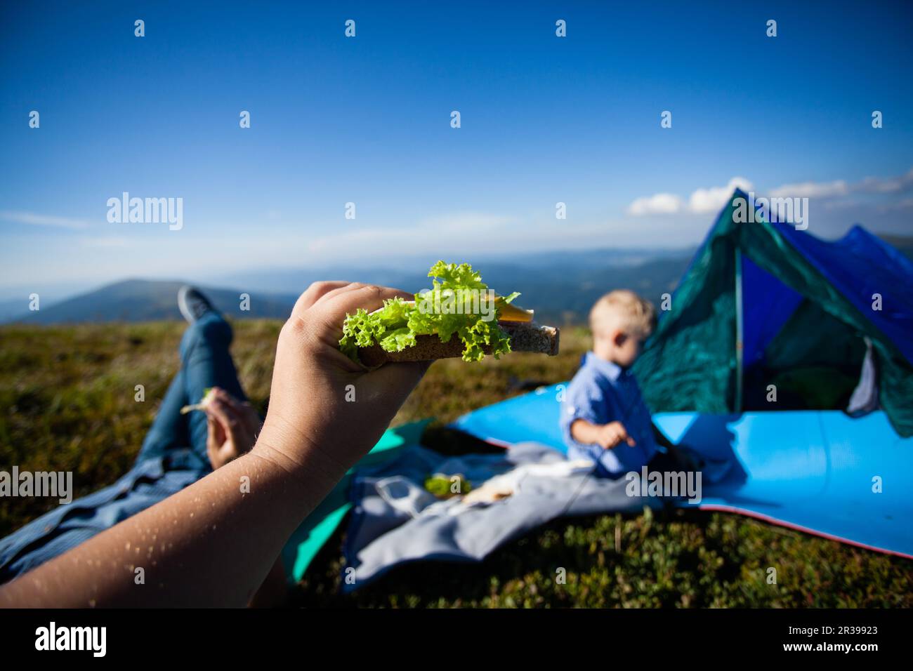 Family snacking at nature. Tasty sandwich with lettuce over sky background. Stock Photo