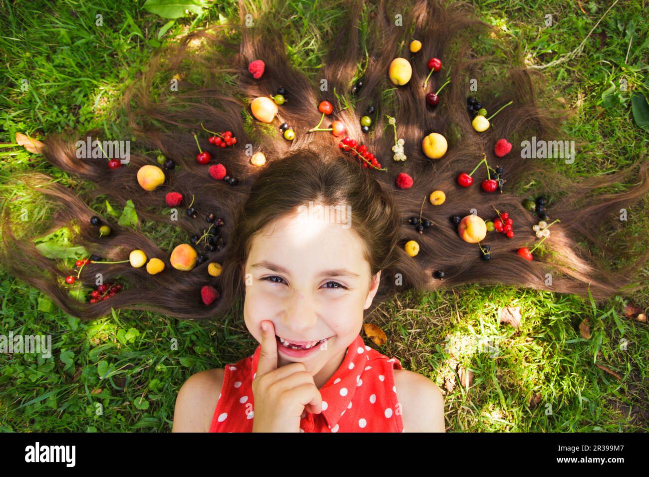 Happy girl think about healthy food lay on the grass Stock Photo