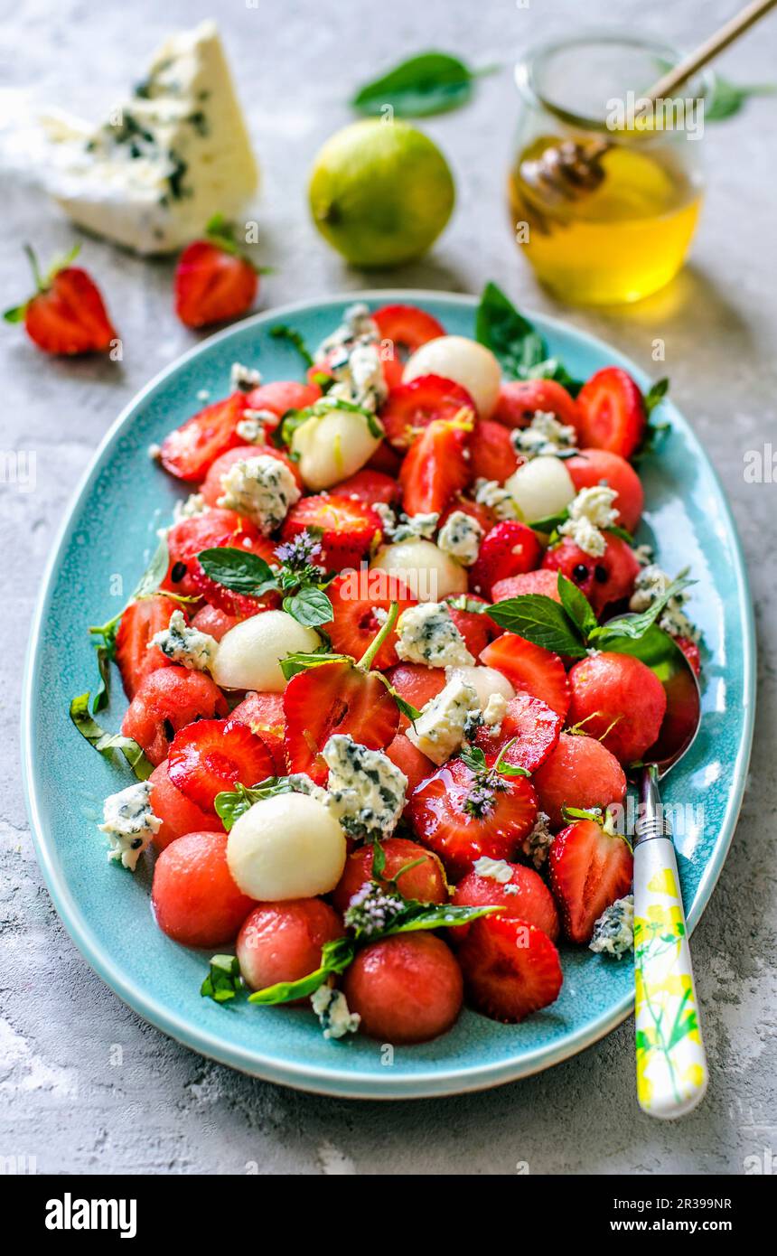 Salad from watermelon, melon, strawberry, basil and blue cheese with honey Stock Photo