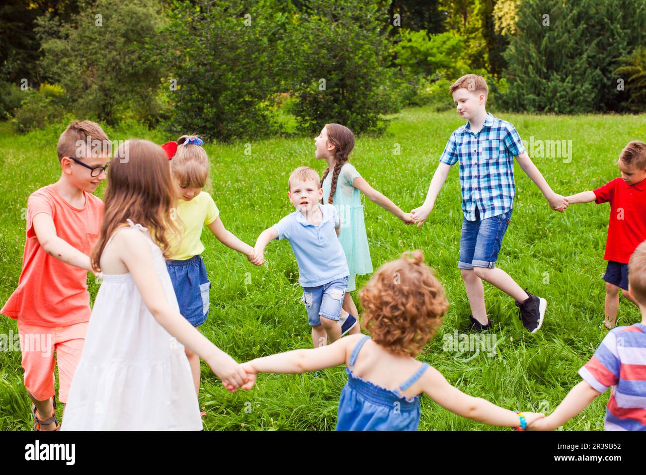 Cute little children doing circle dance outdoors Stock Photo