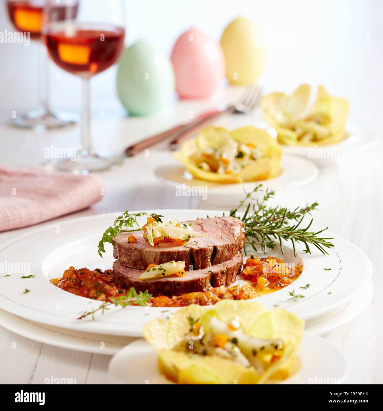 Roasted beef fillets with spicy tomato sauce and fennel in potato baskets Stock Photo