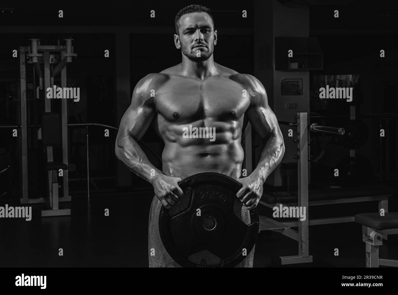 Powerlifter with heavy weight disk in sport gym. Bodybuilder training
