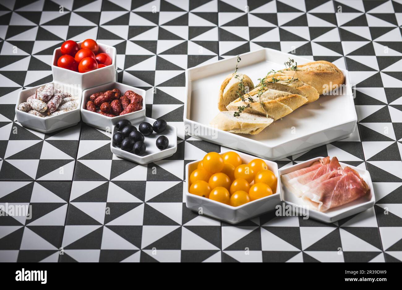 A white baguette with various antipasti on a patterned surface Stock Photo