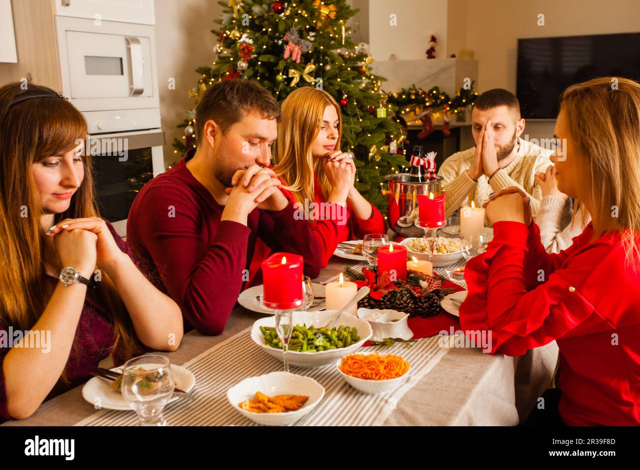 Picture with group of friends praying around Christmas table Stock Photo