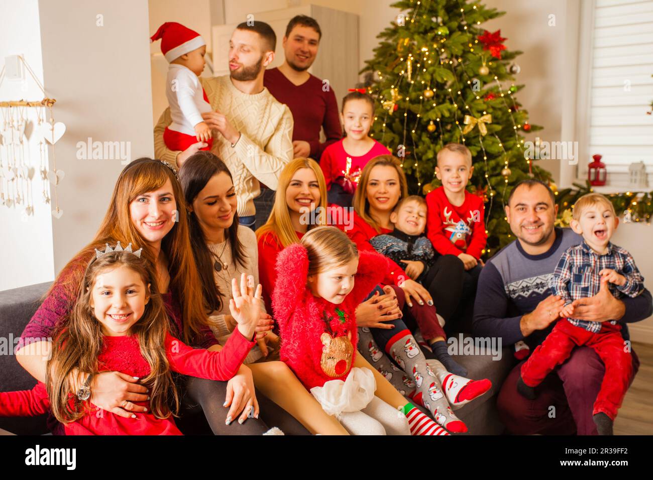 Large family posing on sofa near Christmas tree Stock Photo